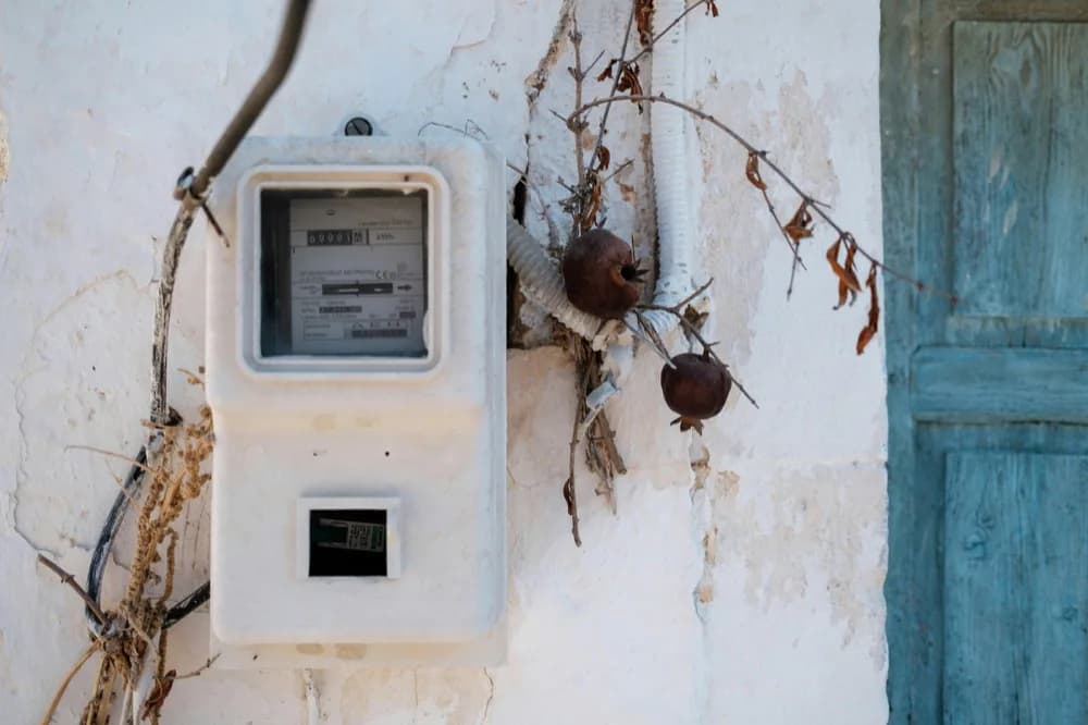 Ancien compteur électrique fixé sur un mur chaulé, près d'une porte