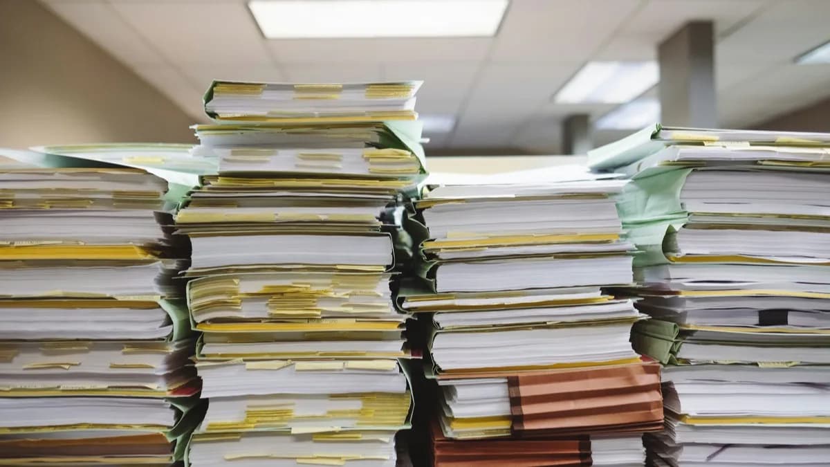Dossiers et feuillets empilés en piles inégales sur un bureau