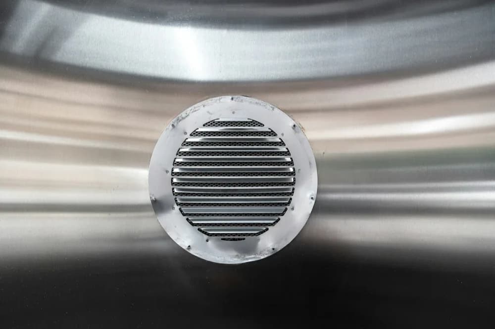 Bouche d'extraction métallique fixée sur une paroi lisse