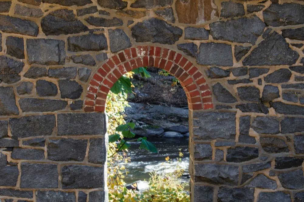 Mur de pierre percé d'une arche, ouvert sur un cours d'eau